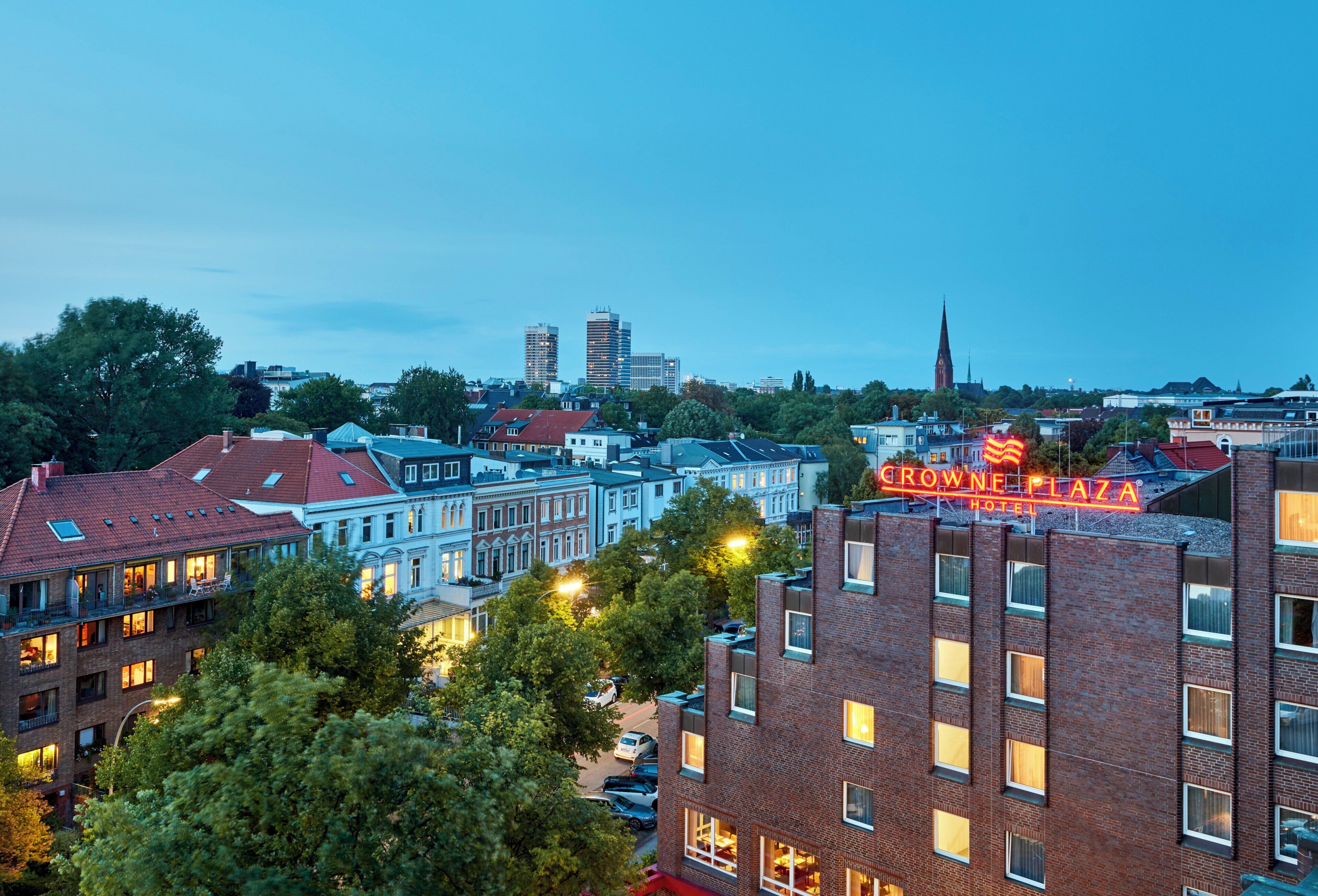 A hotel with multiple stories, featuring a prominent sign and a view of the cityscape in the background.