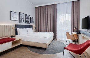 Una habitación de hotel moderna con cama, escritorio, silla y televisión.