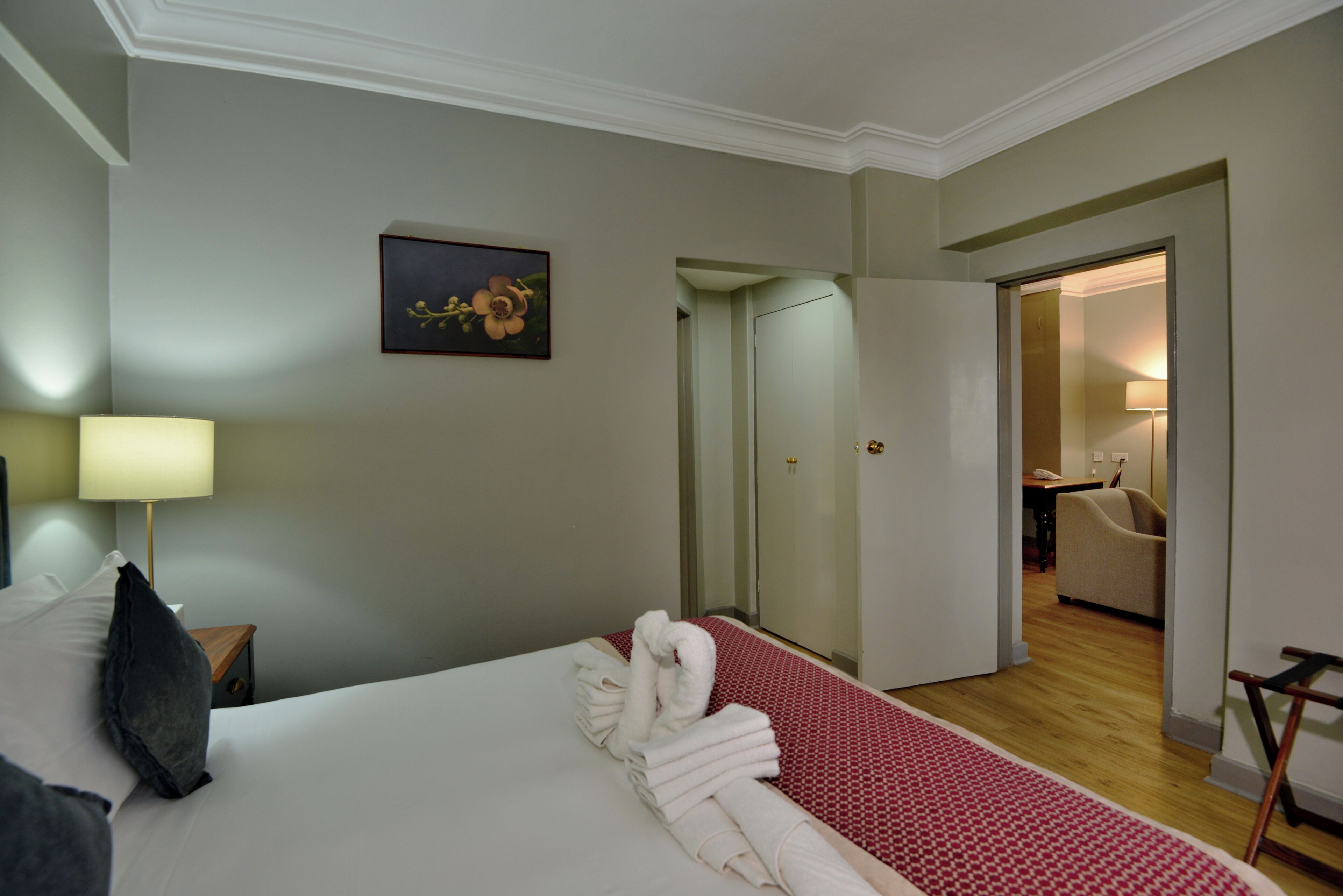 Una habitación de hotel con una cama bien hecha, un cuadro en la pared y una puerta que da a un baño.