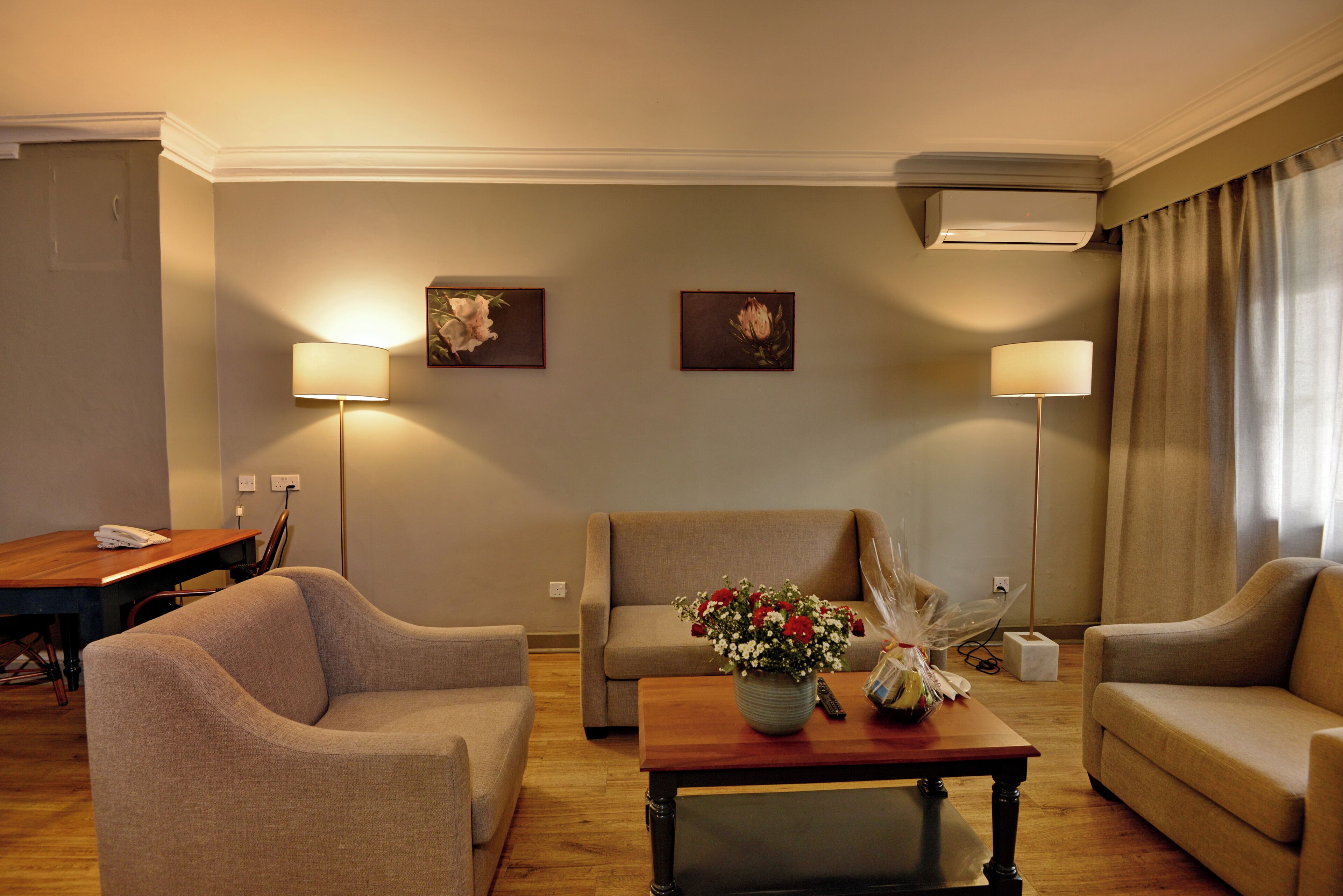 Een hotelkamer met een bank, fauteuil, eettafel en twee wandlampen.