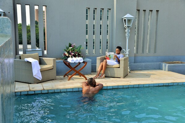 Una piscina al aire libre, sillones reclinables de piscina