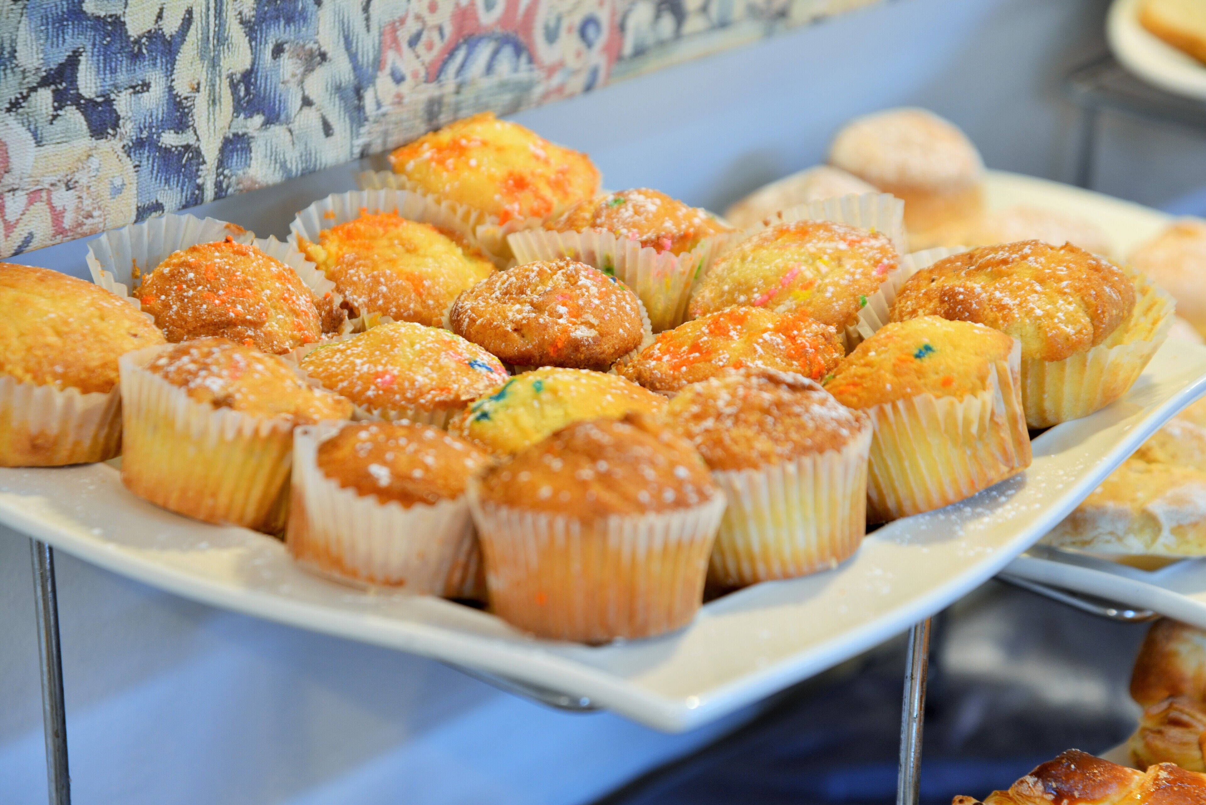 A tray of assorted muffins with various toppings, displayed on a white plate.