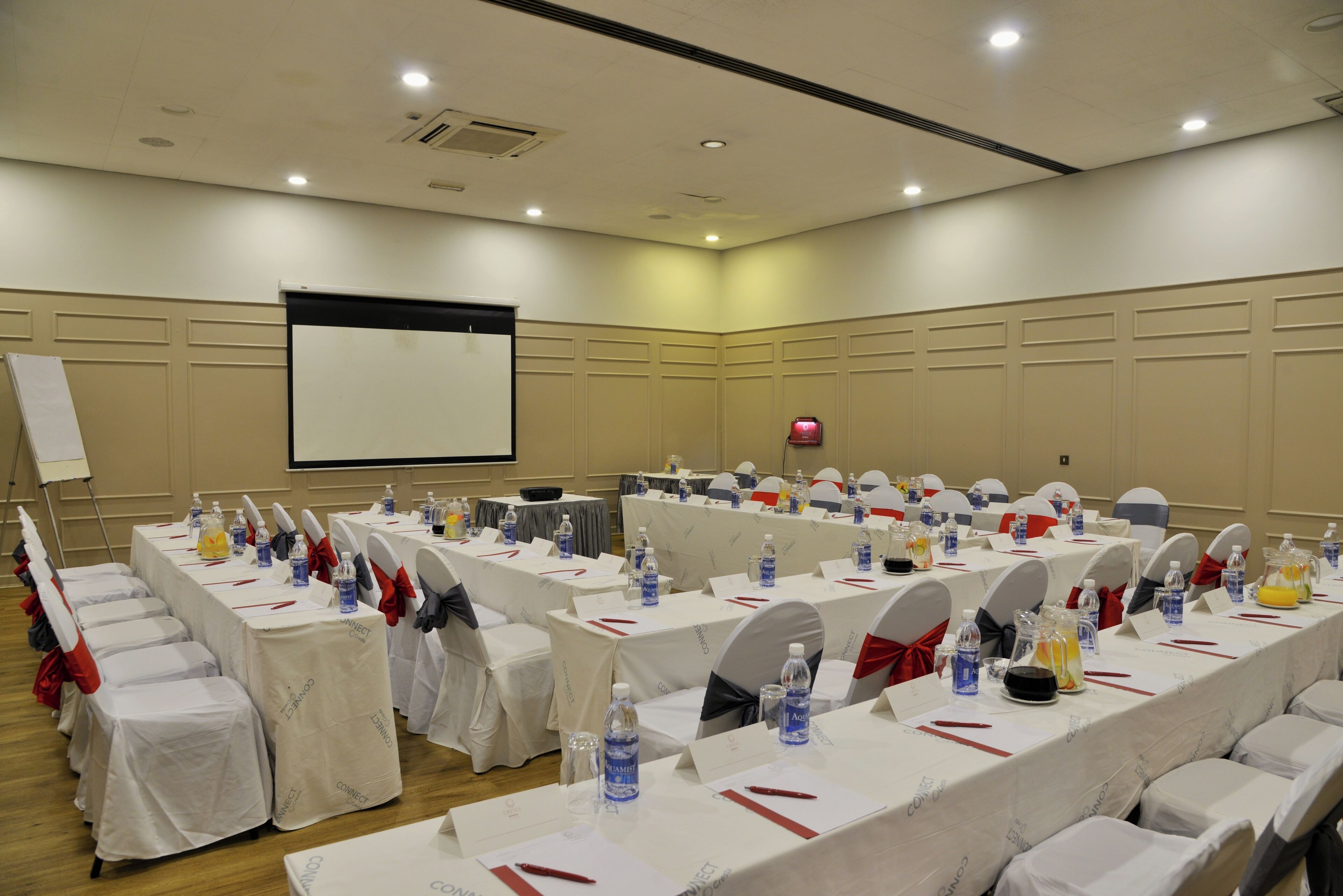 A conference room with multiple tables, chairs, and a projector screen.