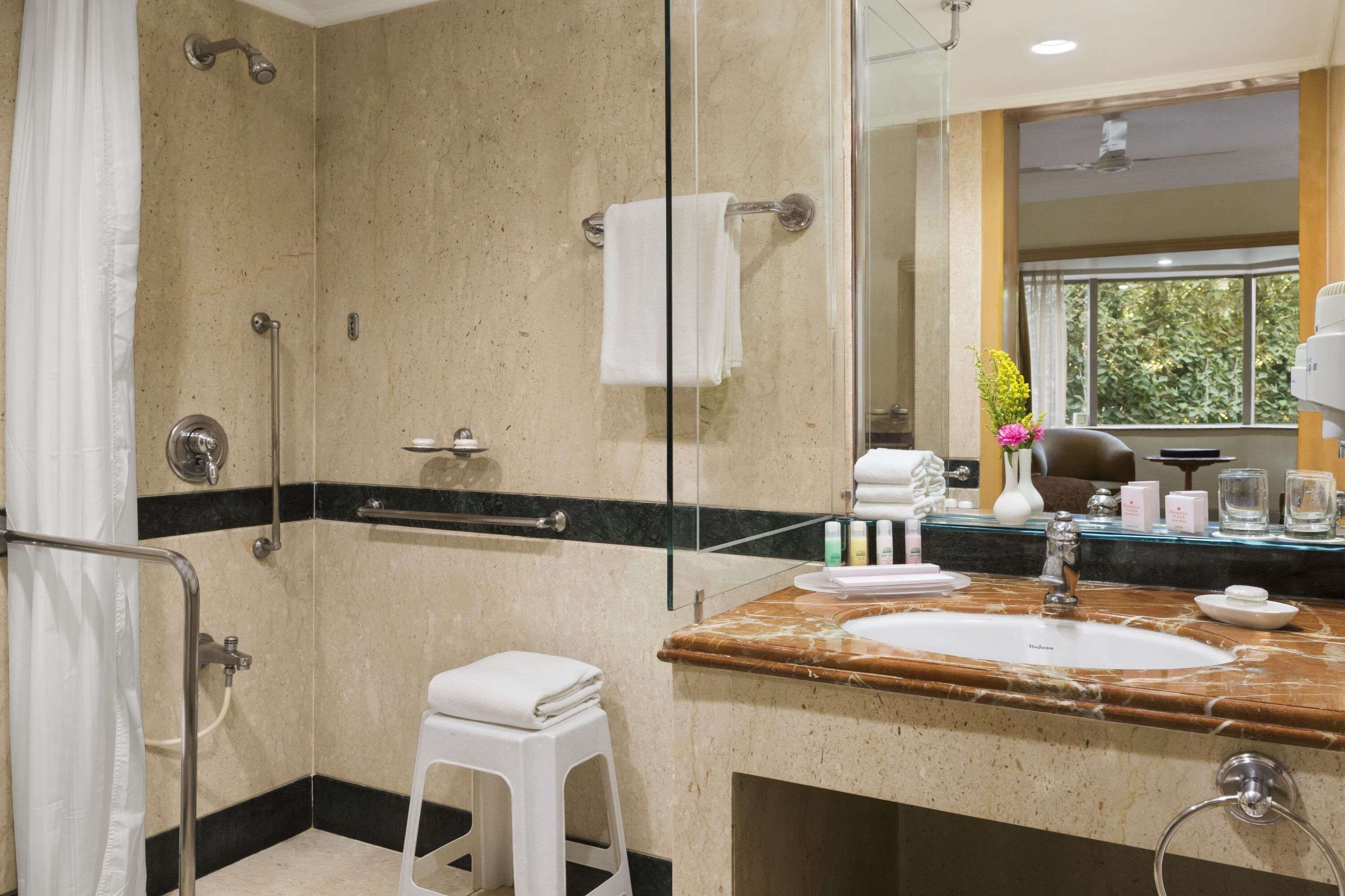 Une salle de bain avec une douche, un lavabo, un miroir et des toilettes.