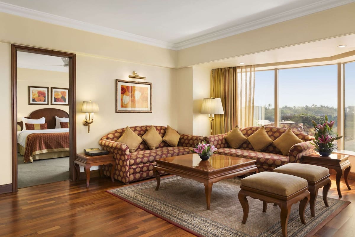 Une chambre d’hôtel avec un grand lit, un canapé, une table basse et une vue sur l’extérieur.