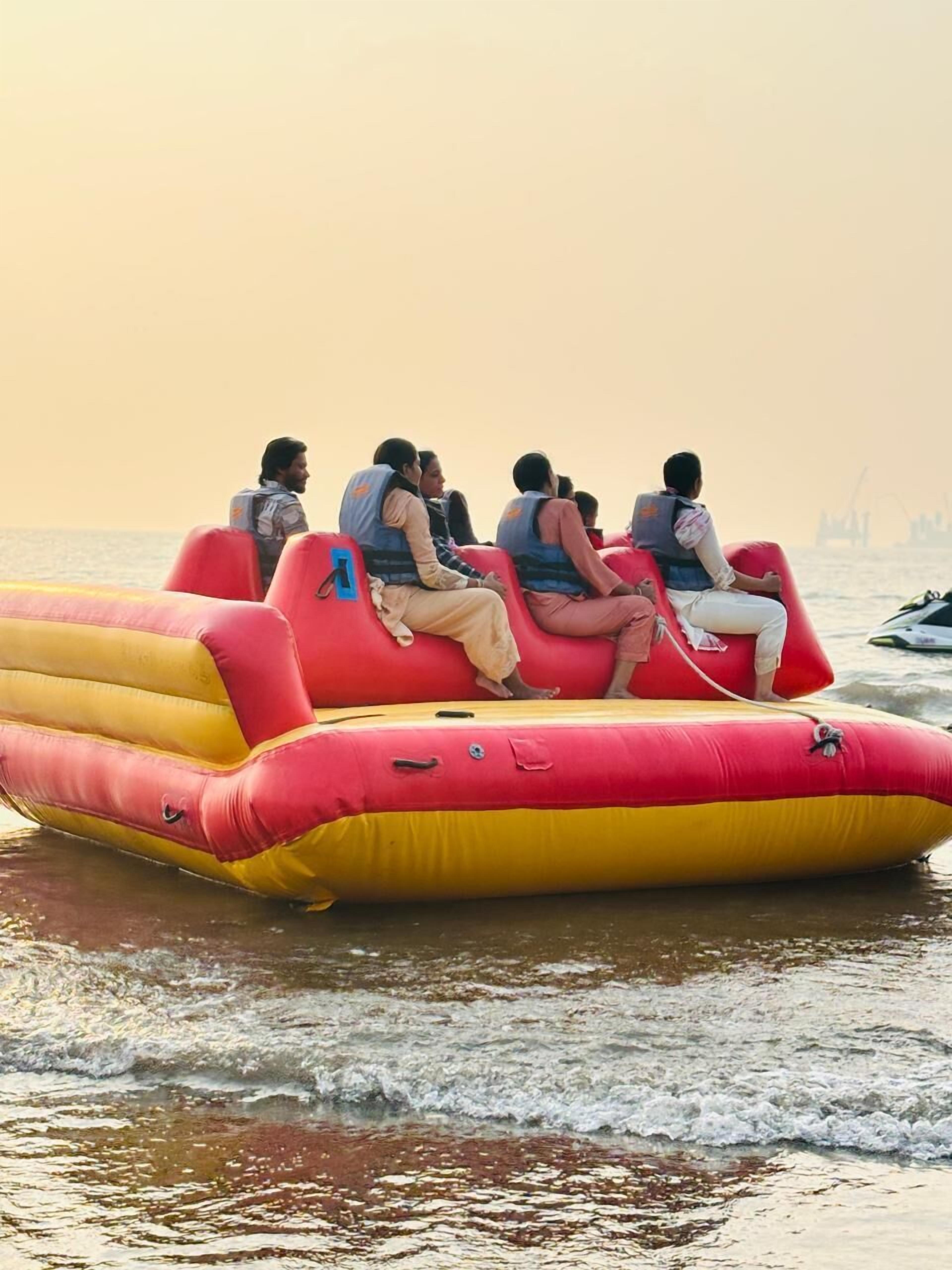 A group of people on a red and yellow inflatable raft on a body of water.