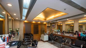 Een moderne kapsalon met meerdere stoelen, een receptiebalie en een grote spiegel.