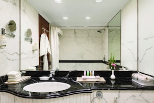 A bathroom with a large mirror, a black marble sink, and a white marble wall.