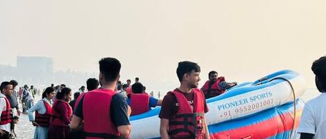 Un grupo de personas con chalecos salvavidas cerca de un bote inflable desinflado.