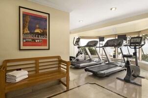 A gym with treadmills, a bench, and a poster of the Middle East.
