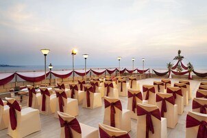 An outdoor seating area with rows of chairs tied with red sashes, arranged in a semi-circular fashion.