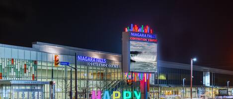 Un centre de congrès doté d’une grande enseigne lumineuse sur laquelle on peut lire « CENTRE DE CONGRÈS DES CHUTES DU NIAGARA » et d’une décoration colorée avec le mot « JOYEUX » à l’avant.