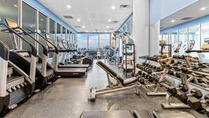 Une salle de sport équipée de tapis de course, d’appareils de musculation et d’haltères.