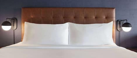 A neatly made bed with a tufted headboard, two bedside lamps, and a plain wall.