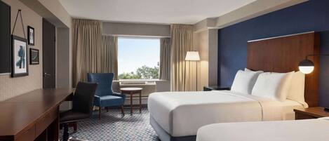 A hotel room with two beds, a desk, a chair, a lamp, and a window with curtains.