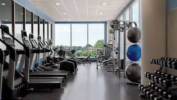 Un gimnasio con cintas de correr, máquinas de pesas y pesas sueltas.