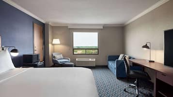 Une chambre d’hôtel avec un grand lit, un bureau, une chaise, une télévision, une lampe et une fenêtre donnant sur un beau paysage.
