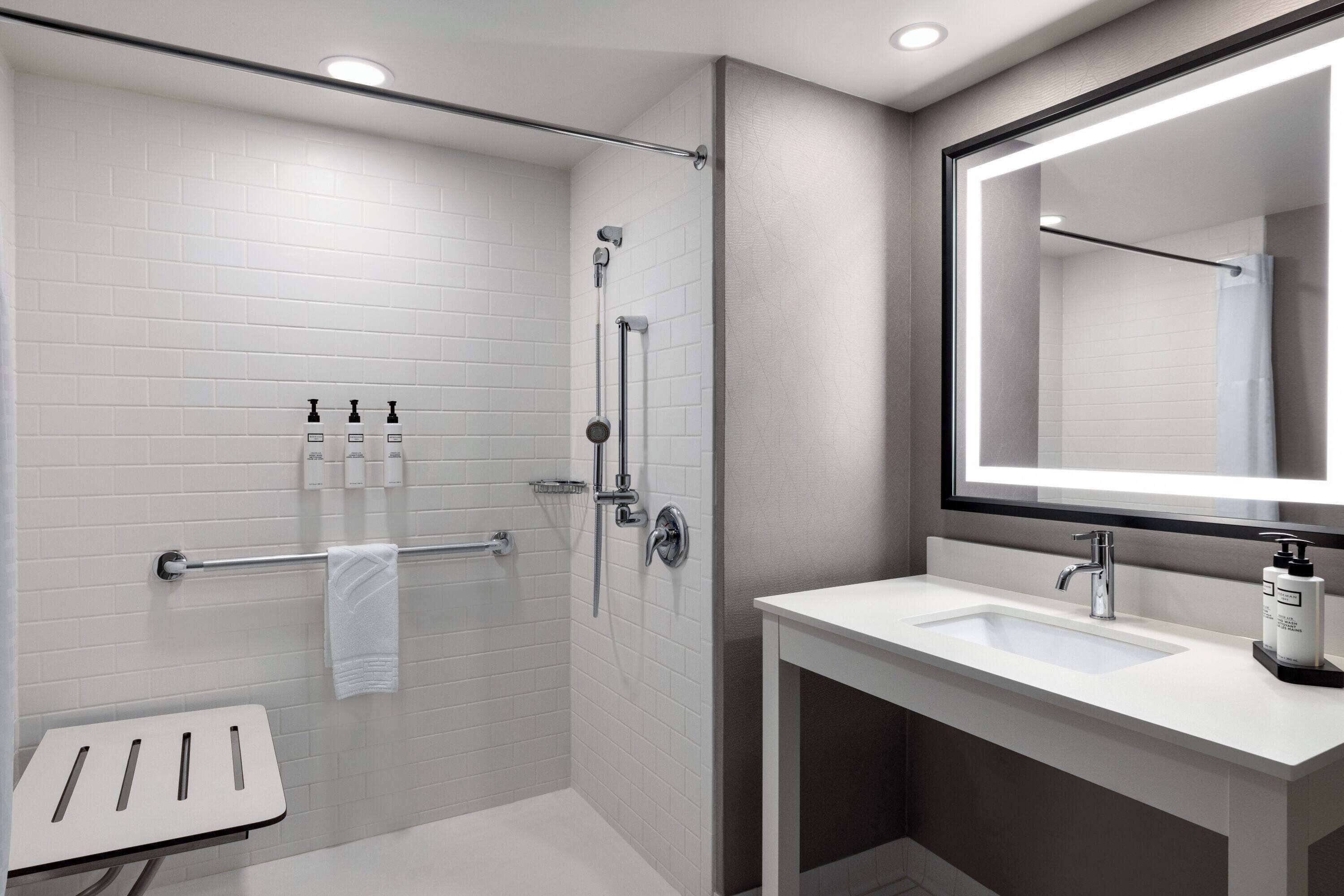 Un baño moderno con ducha, lavamanos y un espejo grande.