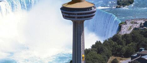 A tower with a viewing platform, overlooking a waterfall and a body of water.