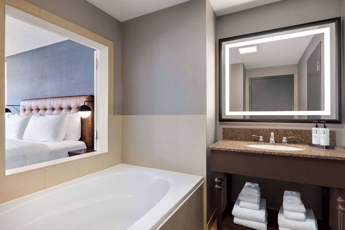 A modern bathroom with a large bathtub, a vanity with a sink, and a mirror.