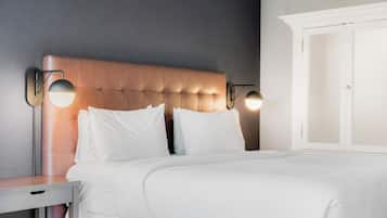 A neatly made bed with white linens, a tufted headboard, and two wall-mounted reading lamps.
