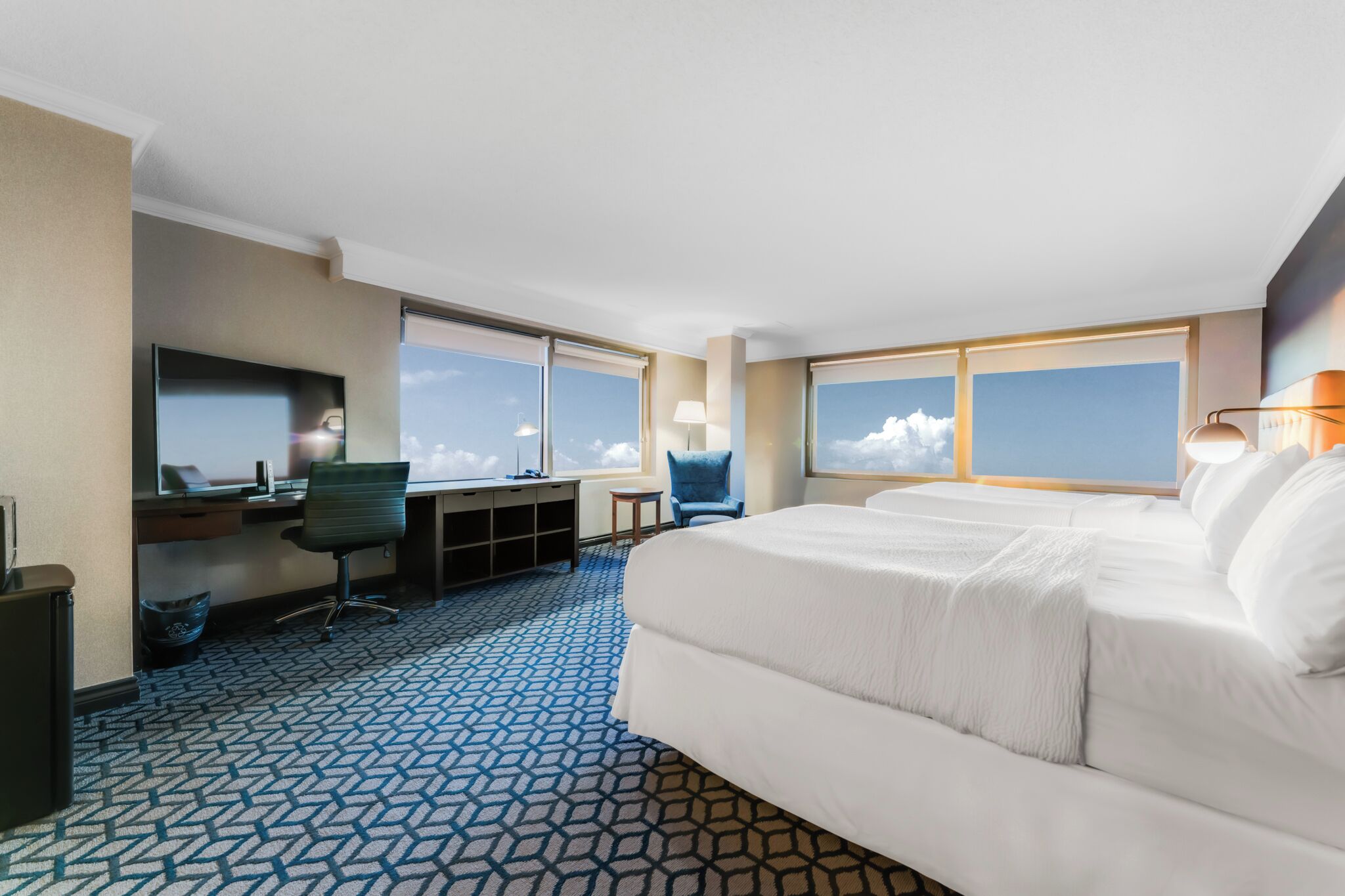 A hotel room with a large bed, a desk with a computer, a chair, and a TV.