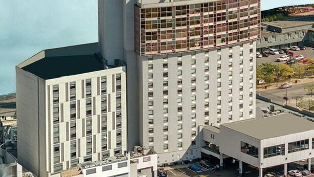 Un hôtel de grande hauteur à l’architecture moderne, caractérisé par une section d’angle imposante dotée de grandes fenêtres.