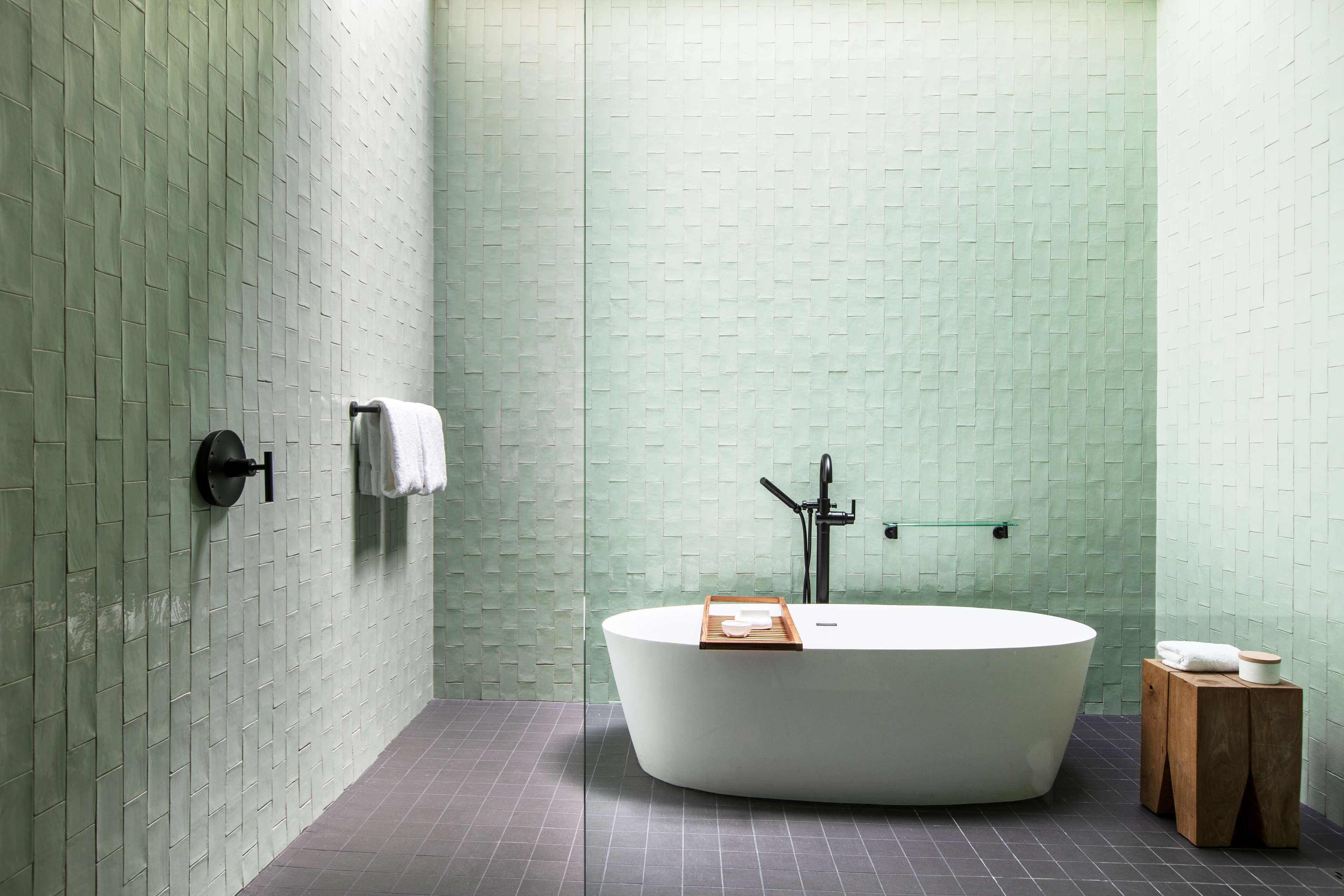 Une salle de bain moderne avec une baignoire sur pieds, un porte-serviettes et un petit tabouret en bois.