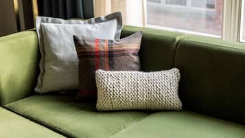 Un sofá verde con tres almohadones de diferentes texturas y diseños.