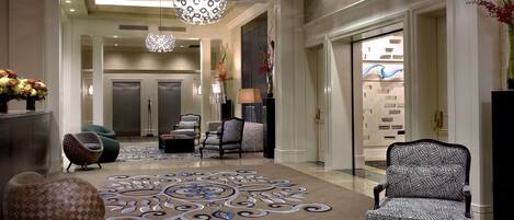 A spacious lobby with a patterned carpet, modern furniture, and a decorative chandelier.