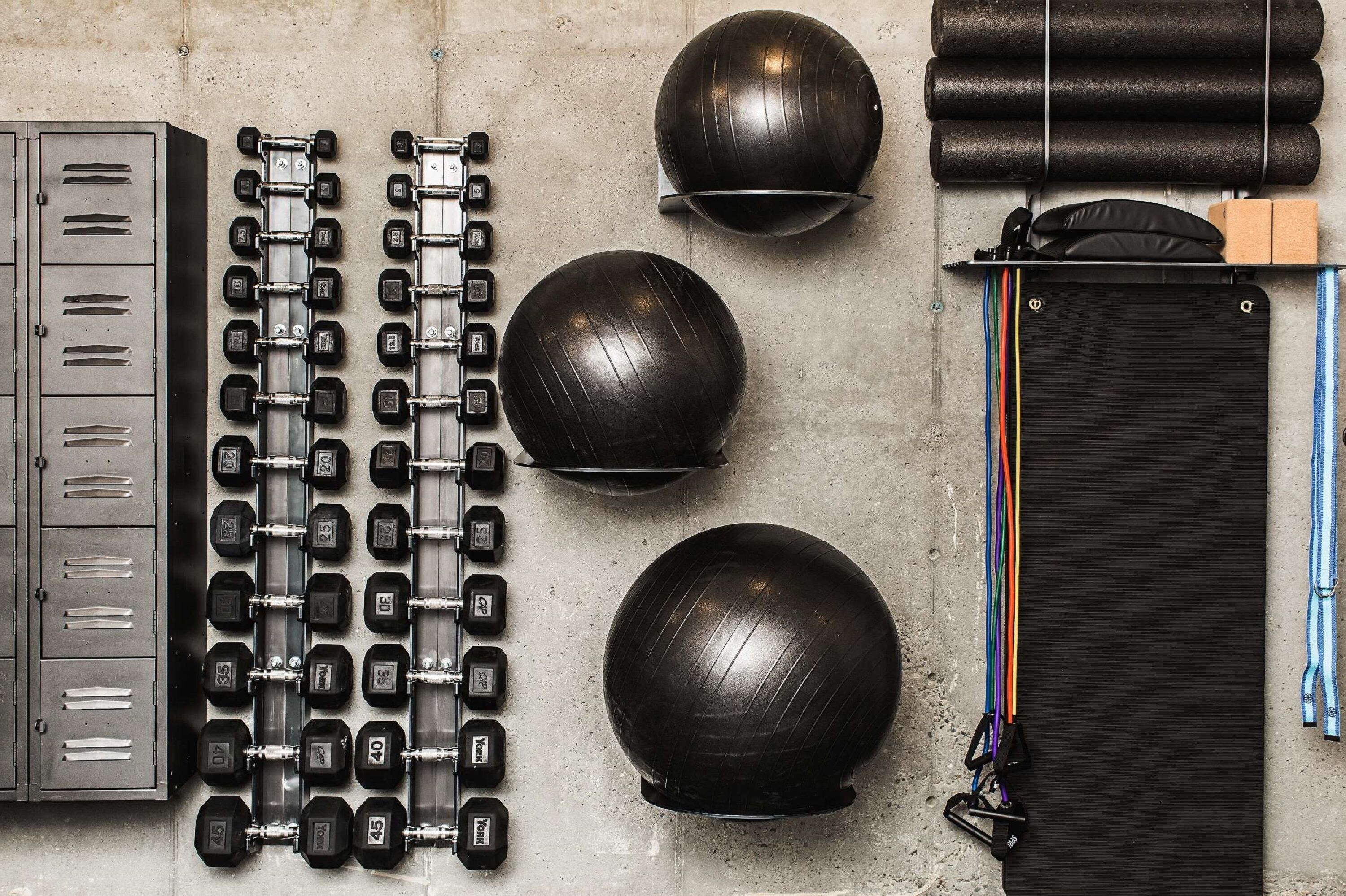 Uma academia com diversos equipamentos de exercícios, incluindo halteres, bolas de medicina e elásticos de resistência.