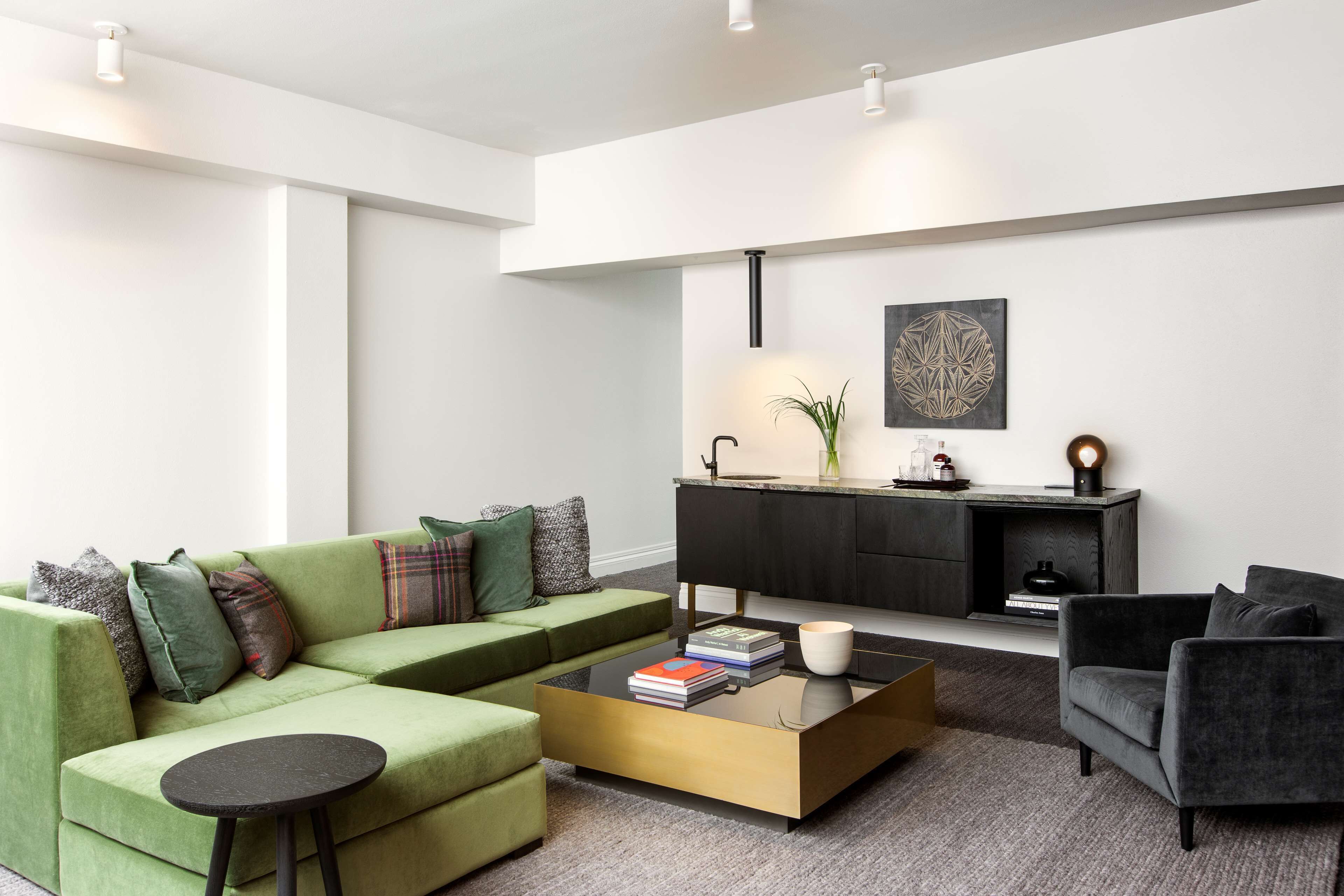 Una sala de estar moderna con un sofá verde, un sillón negro, una mesa de centro y una chimenea.