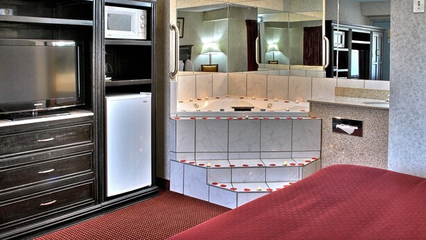 Habitación de hotel con minibar, espejo y zona alfombrada de color rojo.