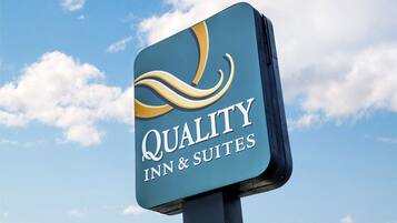 A sign for Quality Inn & Suites against a clear sky.
