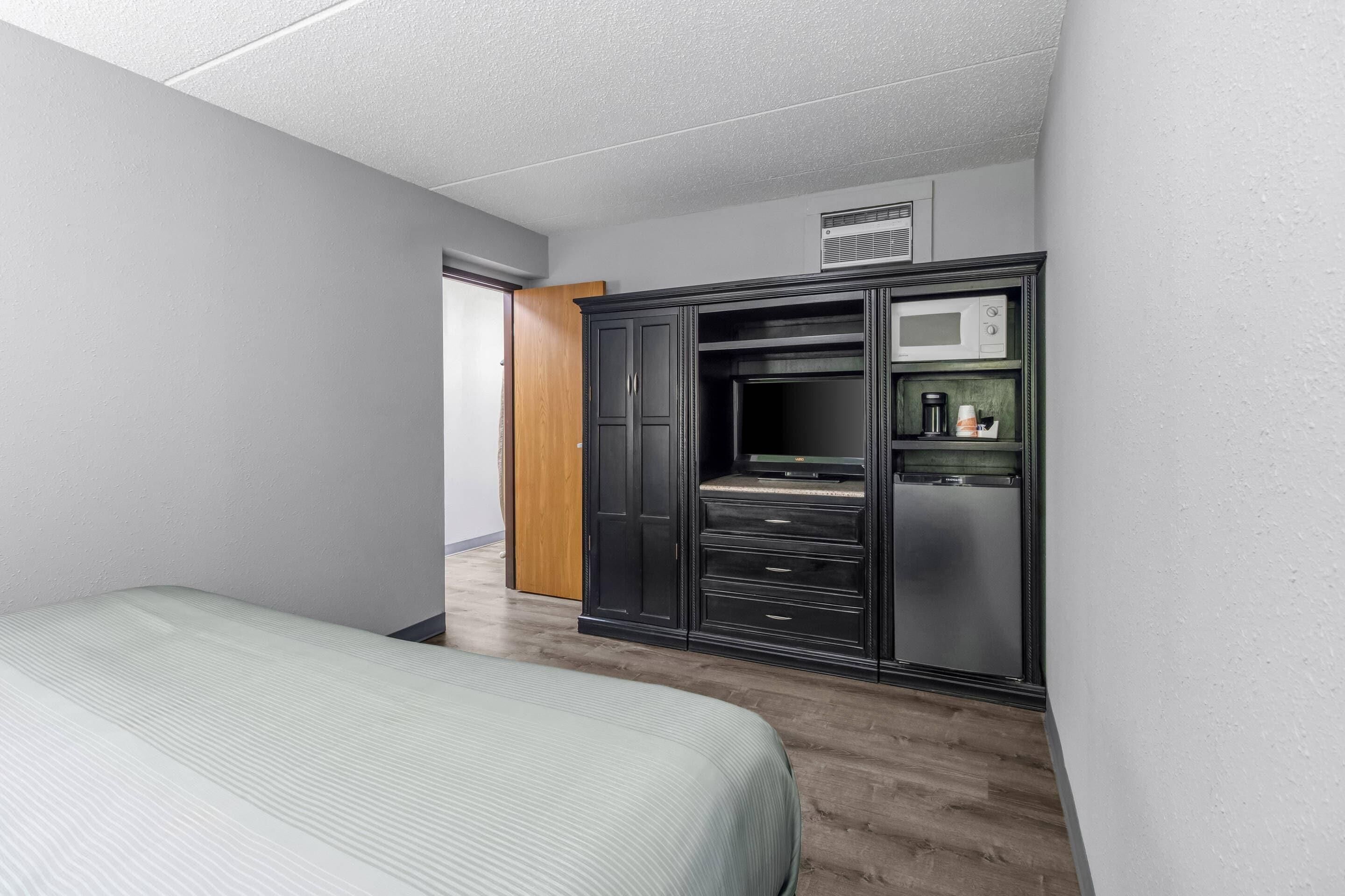 Ein Schlafzimmer mit Bett, Schrank, Schreibtisch und einer Mikrowelle.