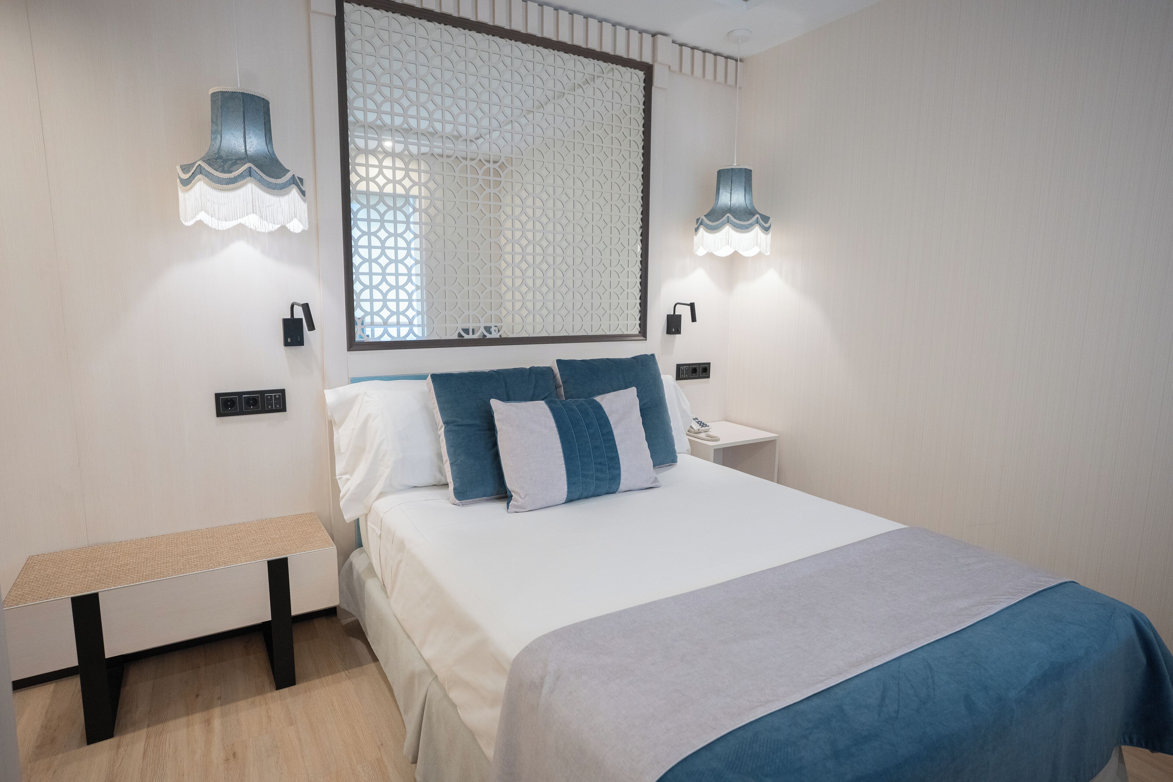A neatly arranged bedroom with a bed, bedside tables, and wall-mounted lamps.