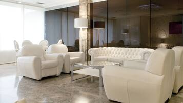 Una sala de estar moderna con un sofá de cuero blanco, sillones a juego y una mesa de centro de vidrio.