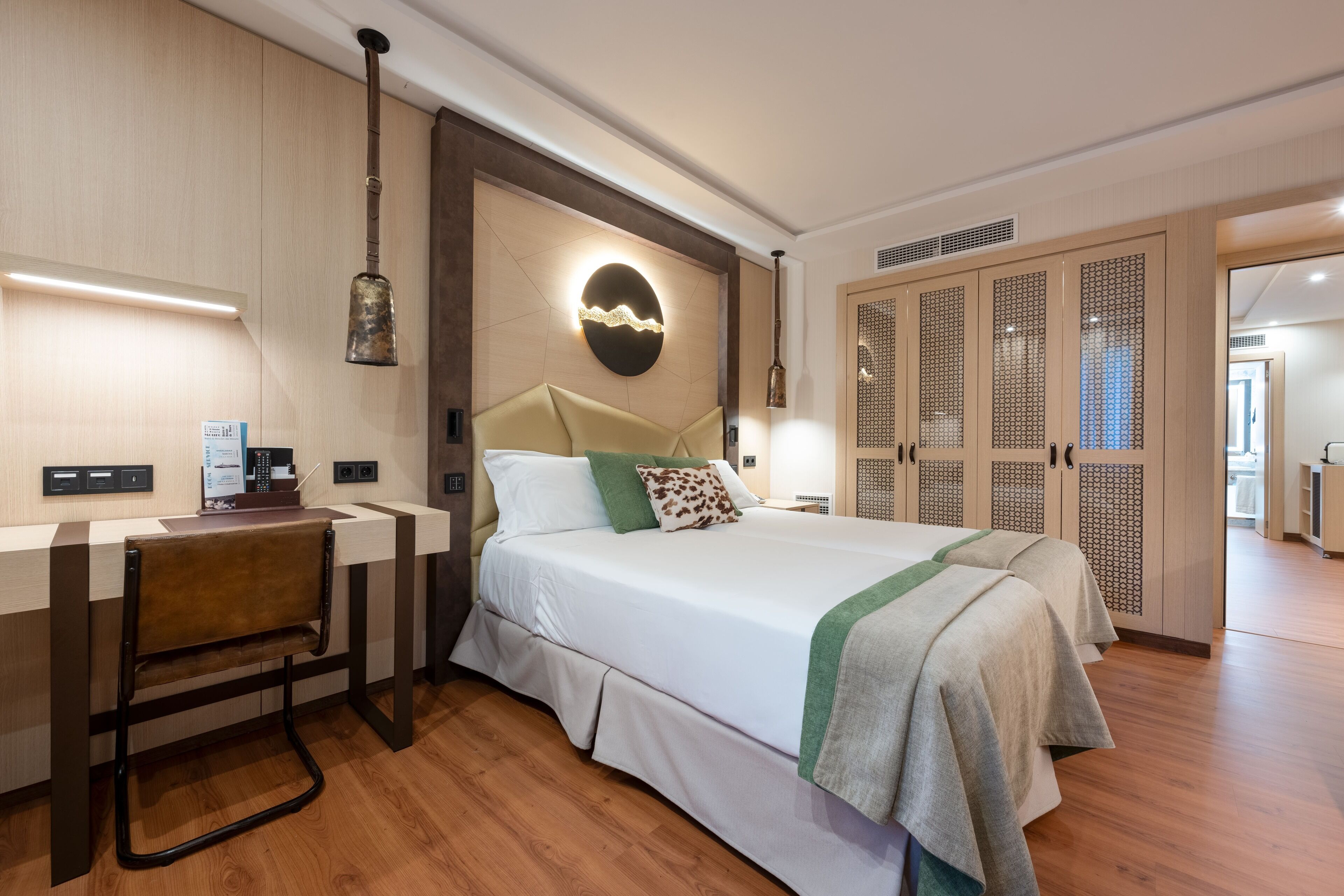 Una habitación de hotel moderna con un escritorio de madera, una cama grande con cabecera y un armario tradicional japonés.