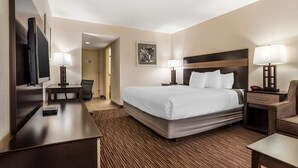 A hotel room with a large bed, a desk, a TV, and a chair. - Best Western Oak Manor (Biloxi)