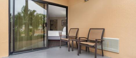 Una habitación con puerta corrediza de vidrio que da a un balcón, una cama y una pequeña mesa con sillas.