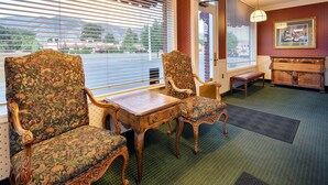 A room with two ornate chairs, a wooden table, and a bench. - Baugh Motel, SureStay Collection by Best Western (Logan)