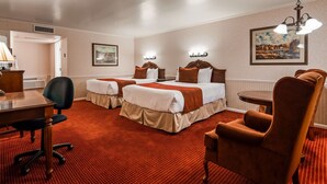 A hotel room with two beds, a desk, a chair, and a small table. - Baugh Motel, SureStay Collection by Best Western (Logan)