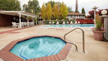 A swimming pool with a hot tub, lounge chairs, and a covered patio area.