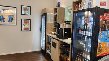 A room with a counter, a refrigerator stocked with beverages, and a display of snacks.