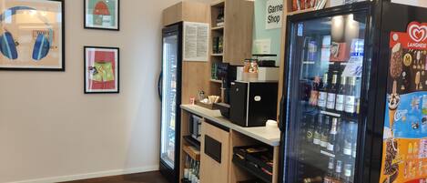 A room with a counter, a refrigerator stocked with beverages, and a display of snacks.
