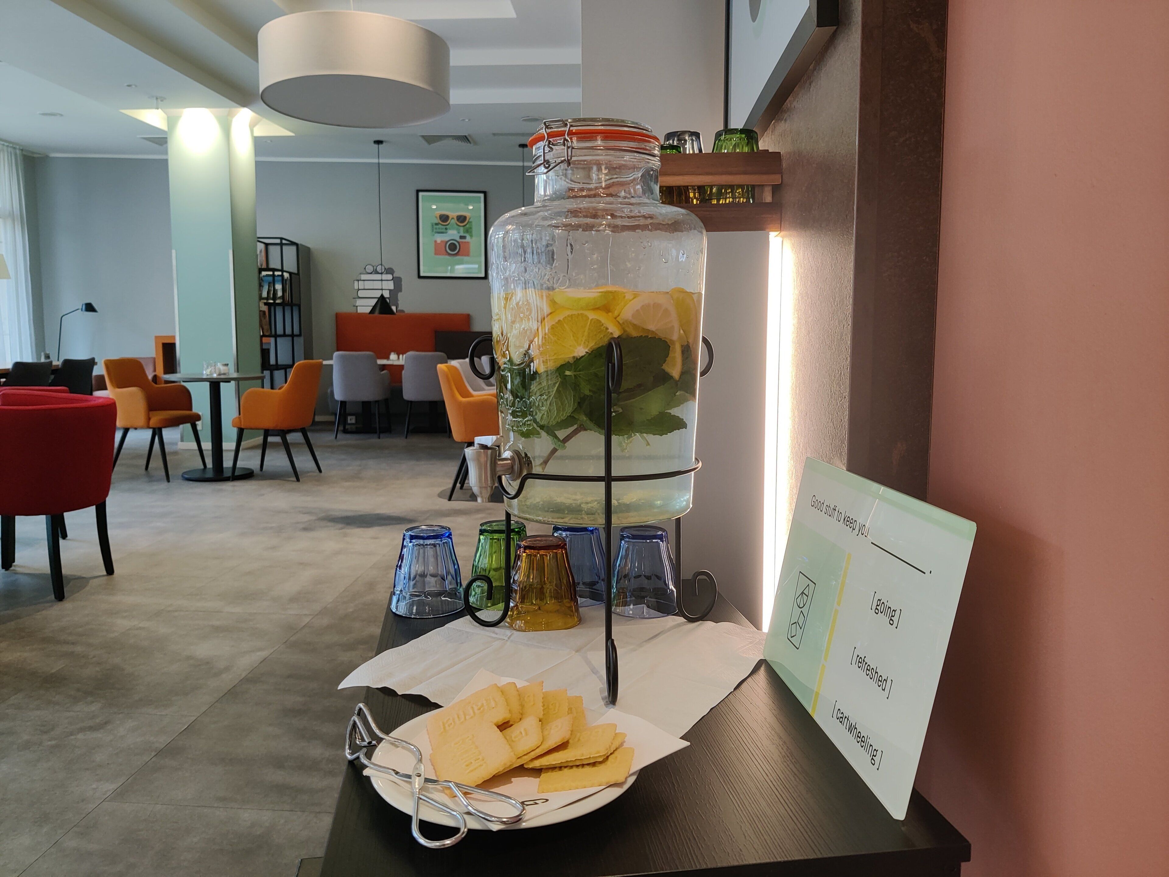 A glass jar with lemon slices and mint leaves, a plate of crackers, and a sign with text.