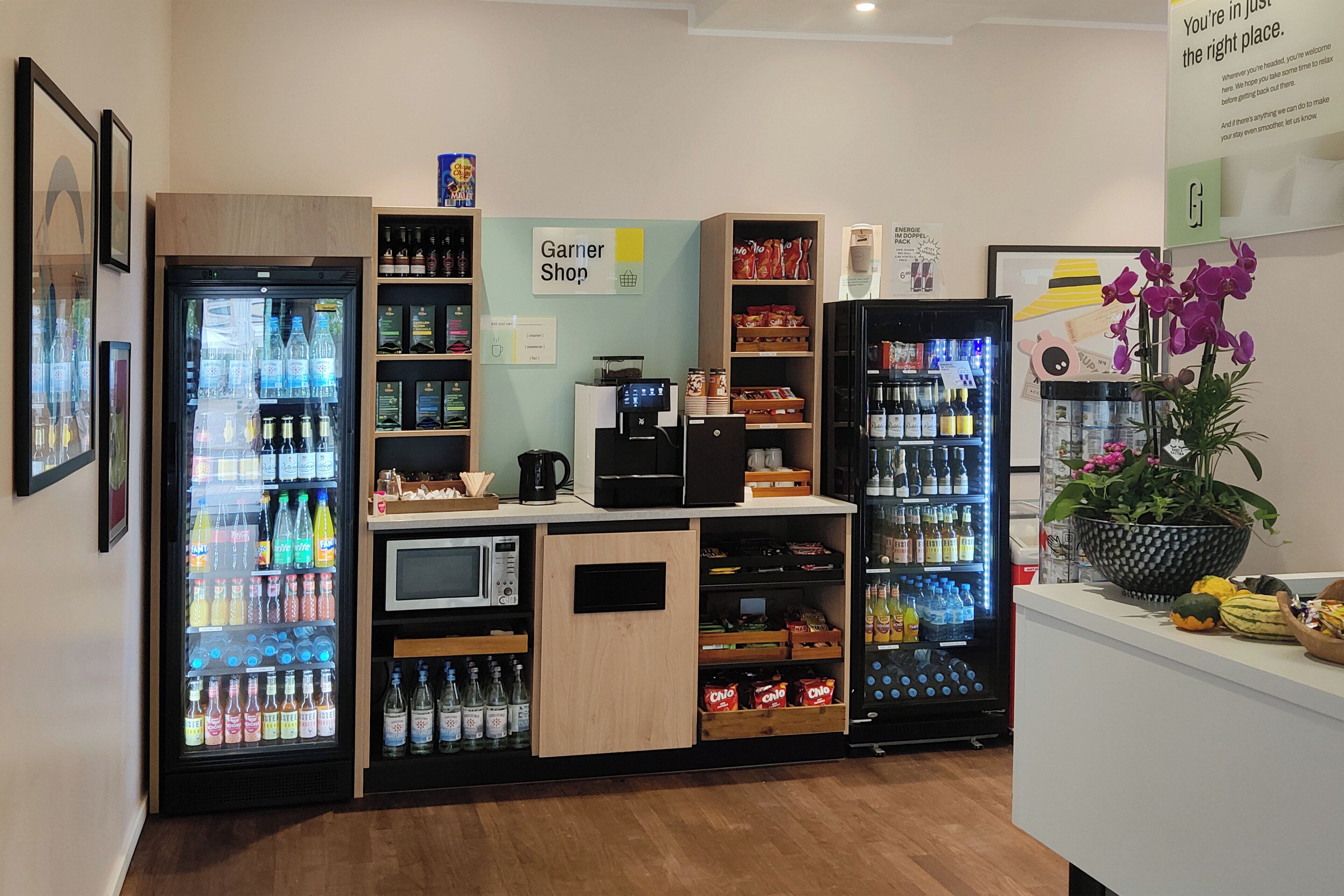 Un espace de vente proposant des distributeurs de boissons réfrigérées, une machine à café et des étagères remplies de collations et de boissons.