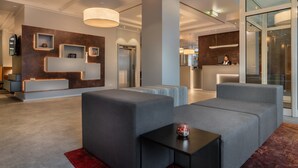 A modern hotel lobby with a reception desk, seating area, and a large pillar. - Garner Hotel Wiesbaden City by IHG (Wiesbaden)