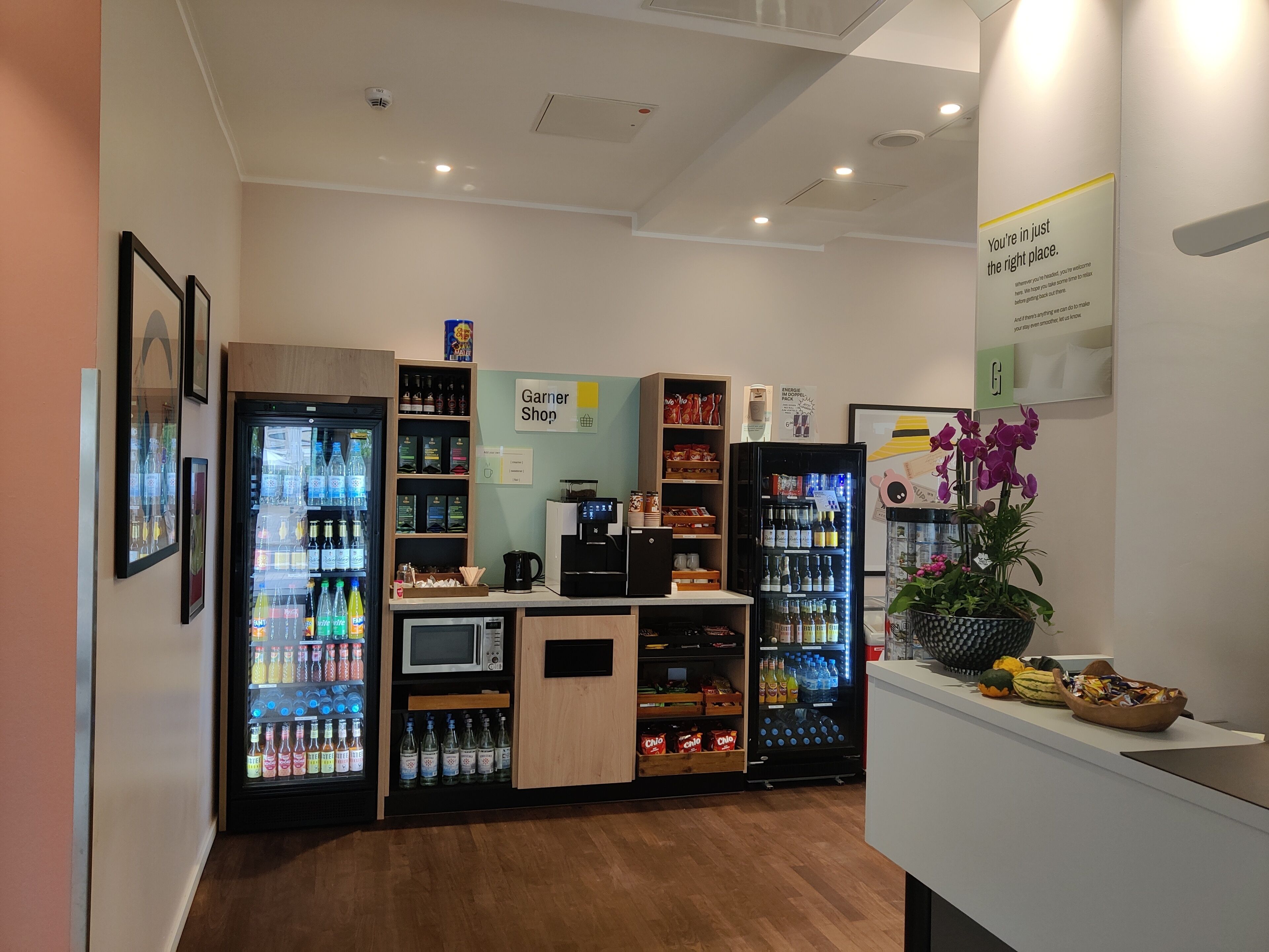 Un espacio interior bien iluminado con máquinas expendedoras, una máquina de café y un letrero que indica una tienda llamada 'Garner Shop'.
