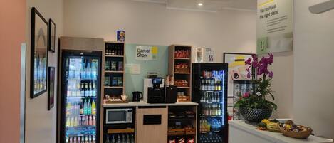 Un espacio interior bien iluminado con máquinas expendedoras, una máquina de café y un letrero que indica una tienda llamada 'Garner Shop'.